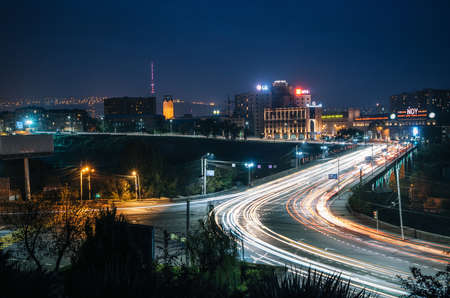 Yerevan, Armenia - October 24, 2016: Night view of The Victory Bridge or Haghtanak Bridge illuminated against Yerevan Ararat Brandy-Wine-Vodka Factory Noy. Armenian landmarkのeditorial素材