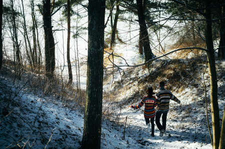 Couple holding hands run away to the forest in winterの写真素材