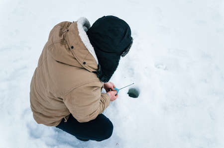 Fisherman on a lake at winter. Ice fishing. View from above close up