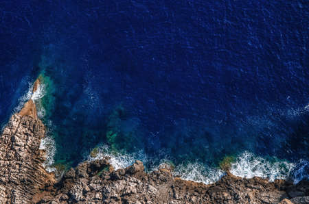 Waves breaking on the shore rocks with sea foam, Mallorcaの写真素材