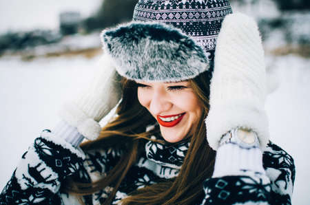 Portrait of handsome young woman wearing warm hat and mittens in winter.の写真素材