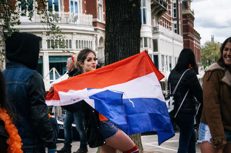 Amsterdam, Netherlands - 27 April, 2017: Beautiful young pretty woman with national Dutch flag. Lifestyle outdoor portrait of girlのeditorial素材