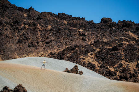 Traveler walks the sand in desert in the valley of the crater of Teide volcano against the mountain, Tenerife, Canary islands, Spainの写真素材