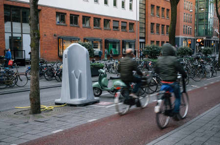 Amsterdam, Netherlands - 26 April, 2017: Cyclists pass in front of outdoor urinal in middle of street in Amsterdamのeditorial素材
