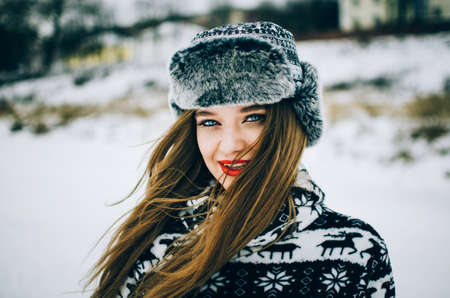 Portrait of handsome young woman with blue eyes looking camera and wearing warm hat in winter.の写真素材