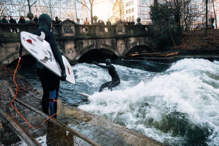 Munich, Germany - December 7, 2017: The surfer in diving suit wait their turn to ride the artificial...
