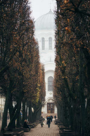 Kaunas, Lithuania - November 7, 2014: Local residents are on the street of Laisves Aleja . St. Michael the Archangels church in a fog on the backgroundのeditorial素材