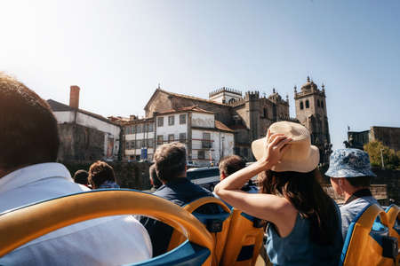 Porto, Portugal. Tourists on open top sightseeing bus Hop on hop off in explore city. Cathedral Seu on the backgroundの写真素材