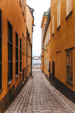 Yellow narrow street in Old Town Gamla Stan of Stockholm, Sweden with view of portの写真素材