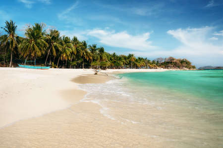 Tropical Malcapuya island with traditional philippines bangka boat, azure water and white sand...