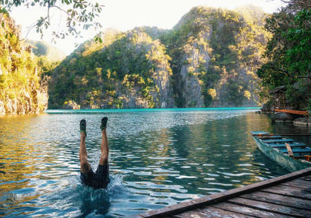 Young man jumps to lake. Legs stick out of water. Kayangan lake, Coron, Philippinesの写真素材