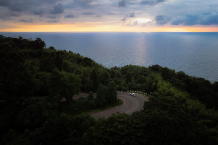 Curvy road winds towards Black sea, with sunset reflecting on water, georgia