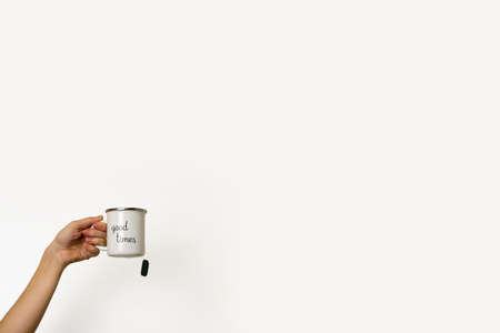 a female hand holds a mug with the inscription "Good things" with tea on the white backgroundの写真素材
