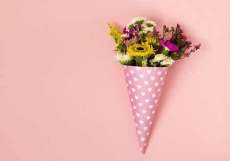 bouquets of flowers in a paper horn with hearts on a blue background. a gift for St. Valentine's Day. gift for International Women's Dayの写真素材