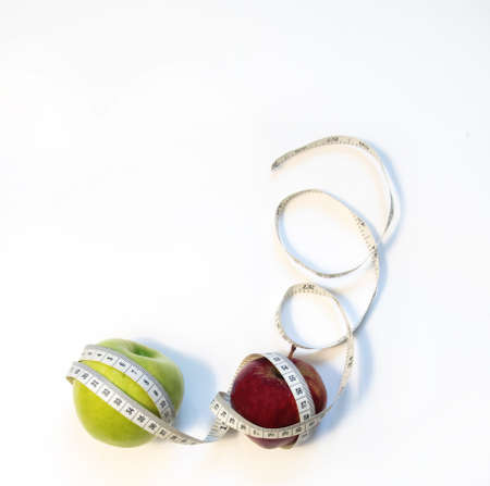 green and red apple wrapped in a measuring tape on a white background. top viewの写真素材