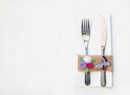white napkin, knife and fork, place for dinner served in rustic style with handmade flower and butterfly on a yellow background.  top view.の写真素材
