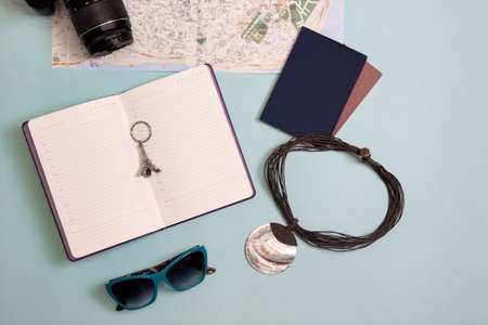 travel items flatlay. on a blue background - a map, a camera, a notebook and a passport. の写真素材