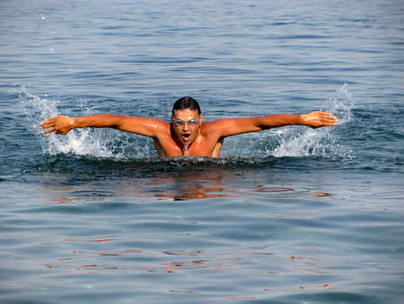 A muscular man swims in the water of Sea
