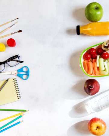 A pile of various stationery on table, notepad, colored pencils, ruler, marker, planer, space for text. Delicious school lunch box, sandwich and fruit. The concept of preparing childrenの写真素材