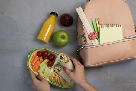 Female hands packing dinner in lunchbox on grey tableの写真素材