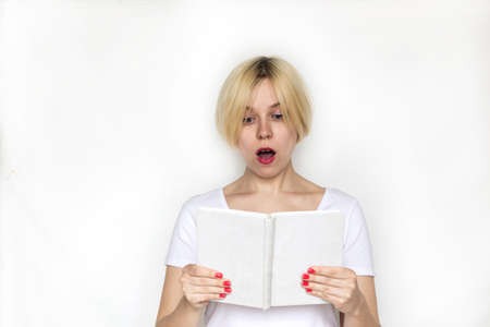 Suprised young woman reading bookの写真素材