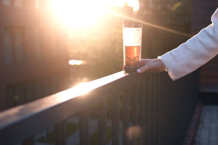 close up woman hand on sunset with cup of teaの写真素材
