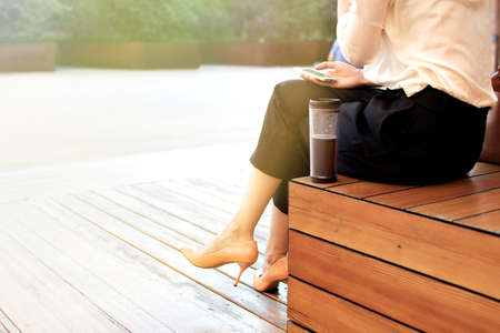 Young attractive woman at the street, browising in internet drinking coffee, Business concept photoの写真素材