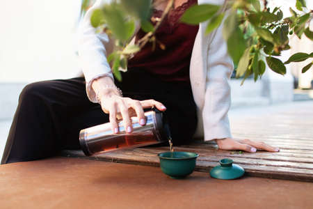 Traveler girl pouring tea in cup  , outdoors. Young woman drinking tea at . Theme travel. Woman pouring a hot drink in mug. gaiwanの写真素材