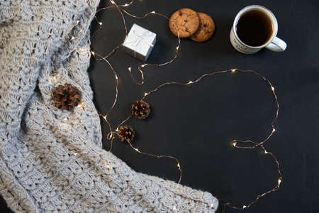 Winter composition. Cup of coffee, cookie, lights on a dark background. Flat layの写真素材