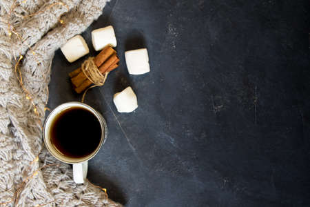 Winter composition. Cup of coffee, cookie, lights on a dark background. Flat lay