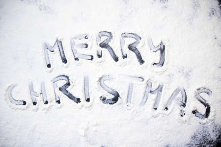Christmas cooking: inscription merry christmas made from flour on a dark table, ingredients for baking and dried fruits on dark backgroundの写真素材