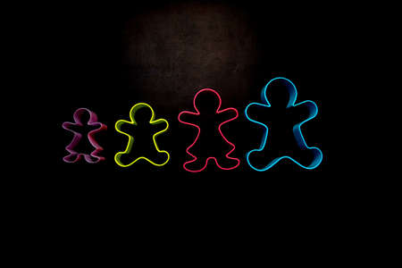 colored gingerbread man shaped food on black backroundの写真素材