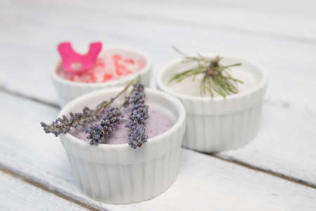 Aromas of bath salt. Rose, lavender and pine near bowls with colorful bath salt on light wooden...