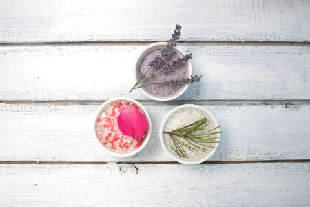 Aromas of bath salt. Rose, lavender and pine near bowls with colorful bath salt on light wooden background top view copy spaceの写真素材
