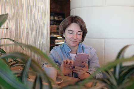 Beautiful senior businesswoman sitting at cafe having telephonic conversation with client. Mature...