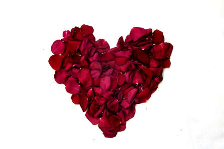 Heart from rose petals arranged in a pattern on a white background.
