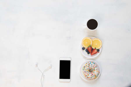 Cup of coffee and donut with curd cream decorated with crumbs of red fruit on white backgroundの写真素材
