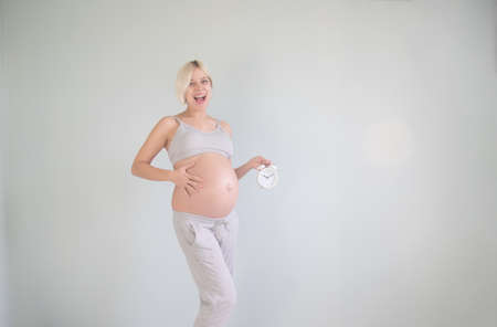 Portrait of amazed pregnant woman holding wall clockの写真素材