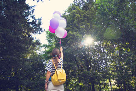 Happy young woman holding colorful latex balloons.の写真素材