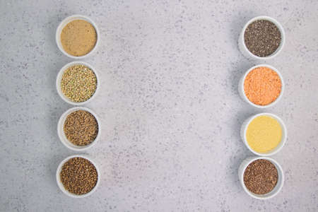 Collection of different groats on grey background. Top view of buckwheat, chia, flax, amaranth, lentils, couscous, wheatの写真素材
