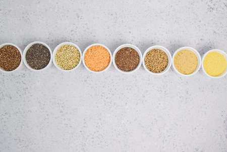 Collection of different groats on grey background. Top view of buckwheat, chia, flax, amaranth, lentils, couscous, wheatの写真素材