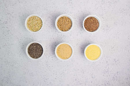 Collection of different groats on grey background. Top view of buckwheat, chia, flax, amaranth, lentils, couscous, wheatの写真素材