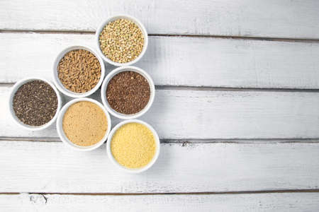 Collection of different groats on grey background. Top view of buckwheat, chia, flax, amaranth, lentils, couscous, wheatの写真素材