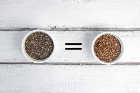 Small bowl with chia seeds and flax seeds with equal sign seen directly from above on grey backgroundの写真素材