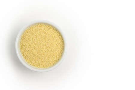 Dry couscous in white ceramic bowl isolated on grey. Spilled couscous. Healthcareの写真素材