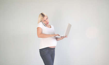 Young beautiful pregnant woman working on laptop. Pregnant business woman searching information and...