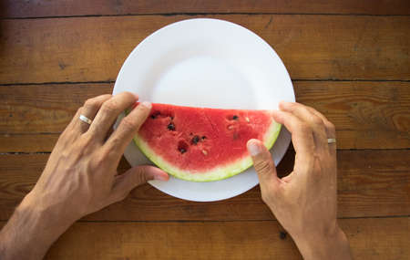 a slice of ripe watermelon in a man's hand, close up.summer timeの写真素材