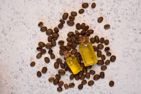 Coffee essential oil in a glass bottle, coffee beans on grey background
