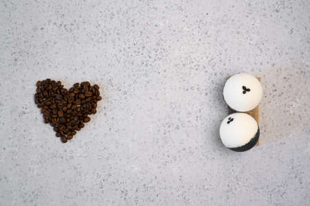 Coffee essential oil in a glass bottle, coffee beans in shape of heart on grey backgroundの写真素材