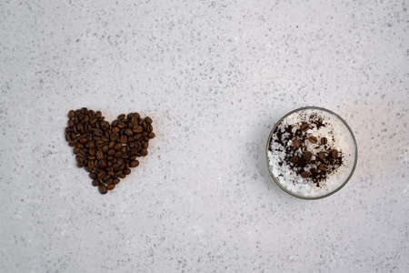 Coffee essential oil in a glass bottle, coffee beans in shape of heart on grey backgroundの写真素材